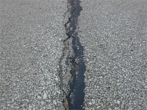 Close-up photo of a single high-severity crack. The crack is sealed, but very wide (i.e., greater than 1 in (25 mm).