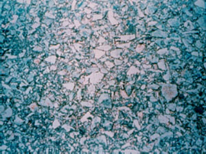 Close-up photo showing exposed aggregate at the pavement's surface. The surface appears to be very smooth, and providing limited skid resistance.