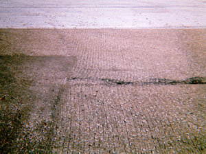 Overview photo showing some signs of slippage cracking, but no visible cracks yet.           In the photo, cut grooves in the pavement surface have noticeably warped due to turning wheels or braking.