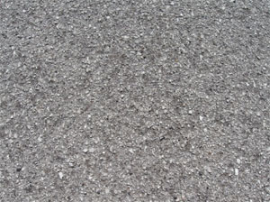 Close-up photo of a small area of asphalt pavement surface with a noticeable loss of coarse aggregate.           The surface is noticeably pitted.