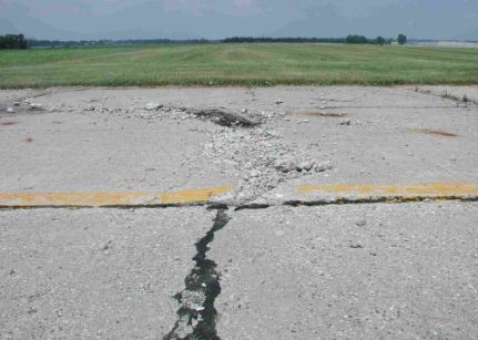 Overview photo of a transverse PCC joint with a high-severity blowup. Both slabs have considerable spalling due to the blowup.