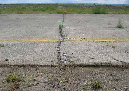 Overview photo of a transverse PCC joint with a low-severity blowup. A slight difference in height is noticeable between the two slabs.