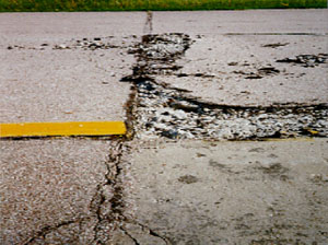 Overview photo of a transverse PCC joint with a medium-severity blowup. Both slabs show some distress at the joint, but the right slab has considerable spalling due to the blowup.