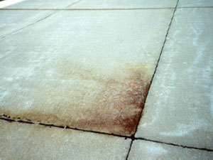 Overview photo of a slab corner where the pavement surface at the corner is discolored. The discoloring (or staining)           of the surface is actually subgrade material that has been ejected from the subgrade due to pumping.