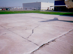 Overview photo showing a slab that is broken into four or five larger pieces.           The cracks that divide the pieces are medium-severity cracks.