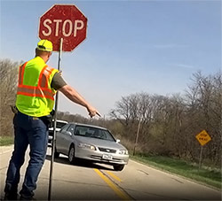 Flagger pointing car to next lane