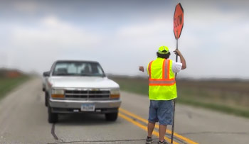 Flagger turning sign to allow cars through